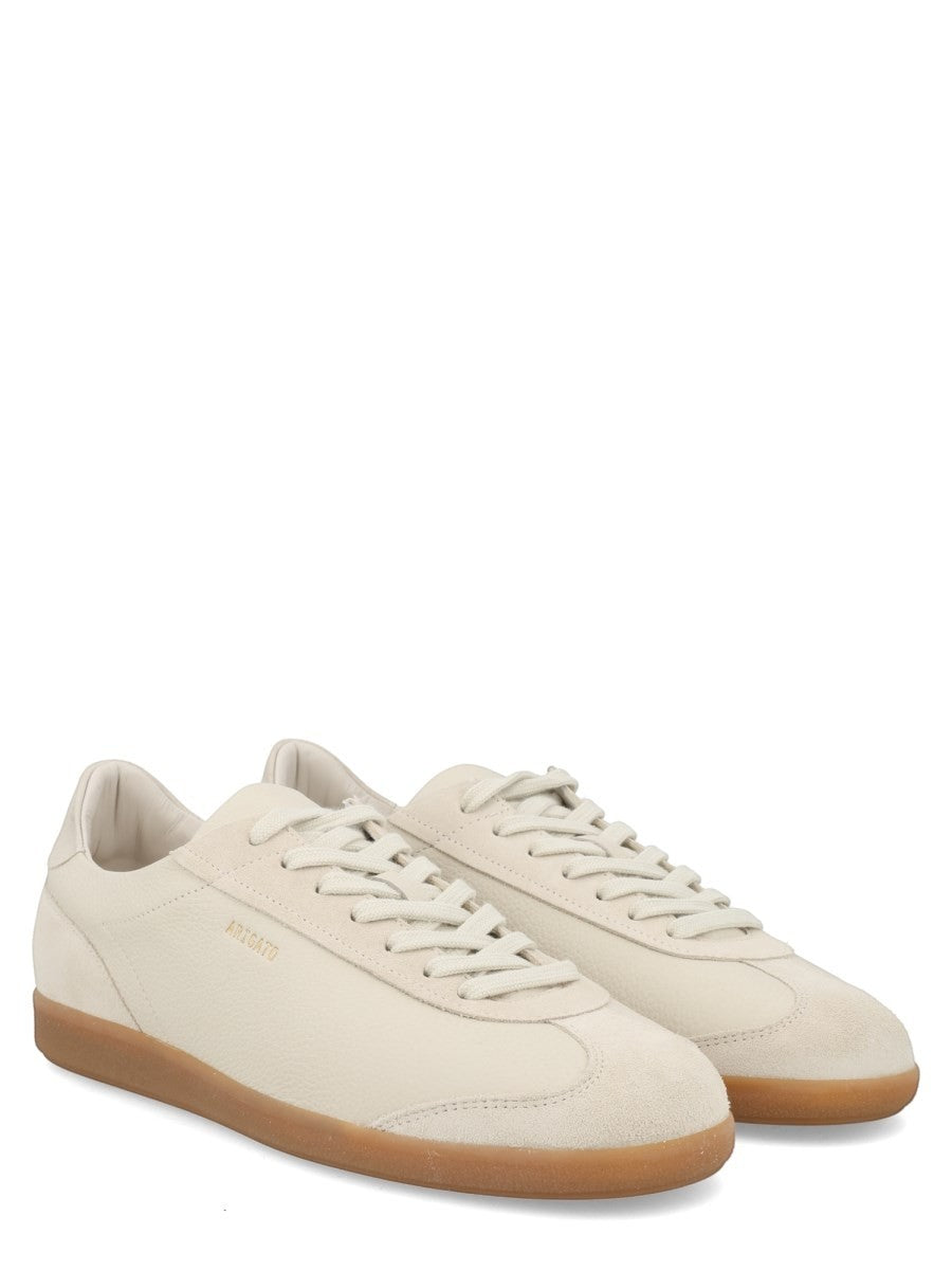 Three-quarter view of the AXEL ARIGATO Zane sneaker in off white leather with suede details and translucent gum sole.