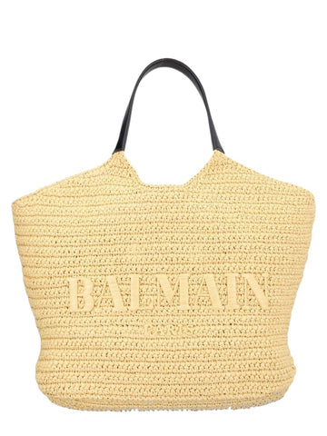 Front view of the Balmain Crochet Shopper Bag in natural, showcasing the oversized embroidered Balmain Paris logo, hand-crocheted raffia body and black leather shoulder handles.