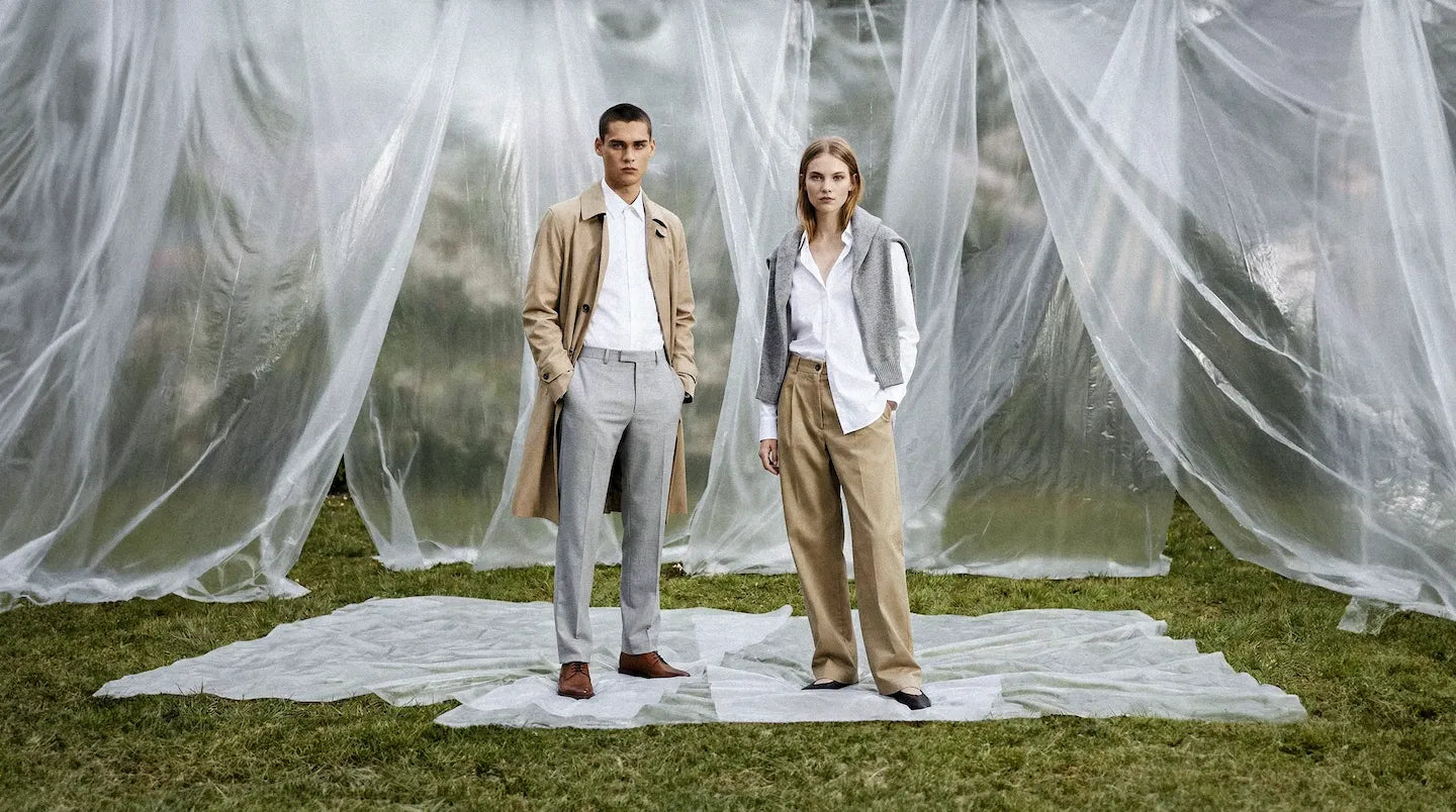 Fashion models in neutral tailoring standing outdoors with sheer fabric backdropslider_item_6FrBi8