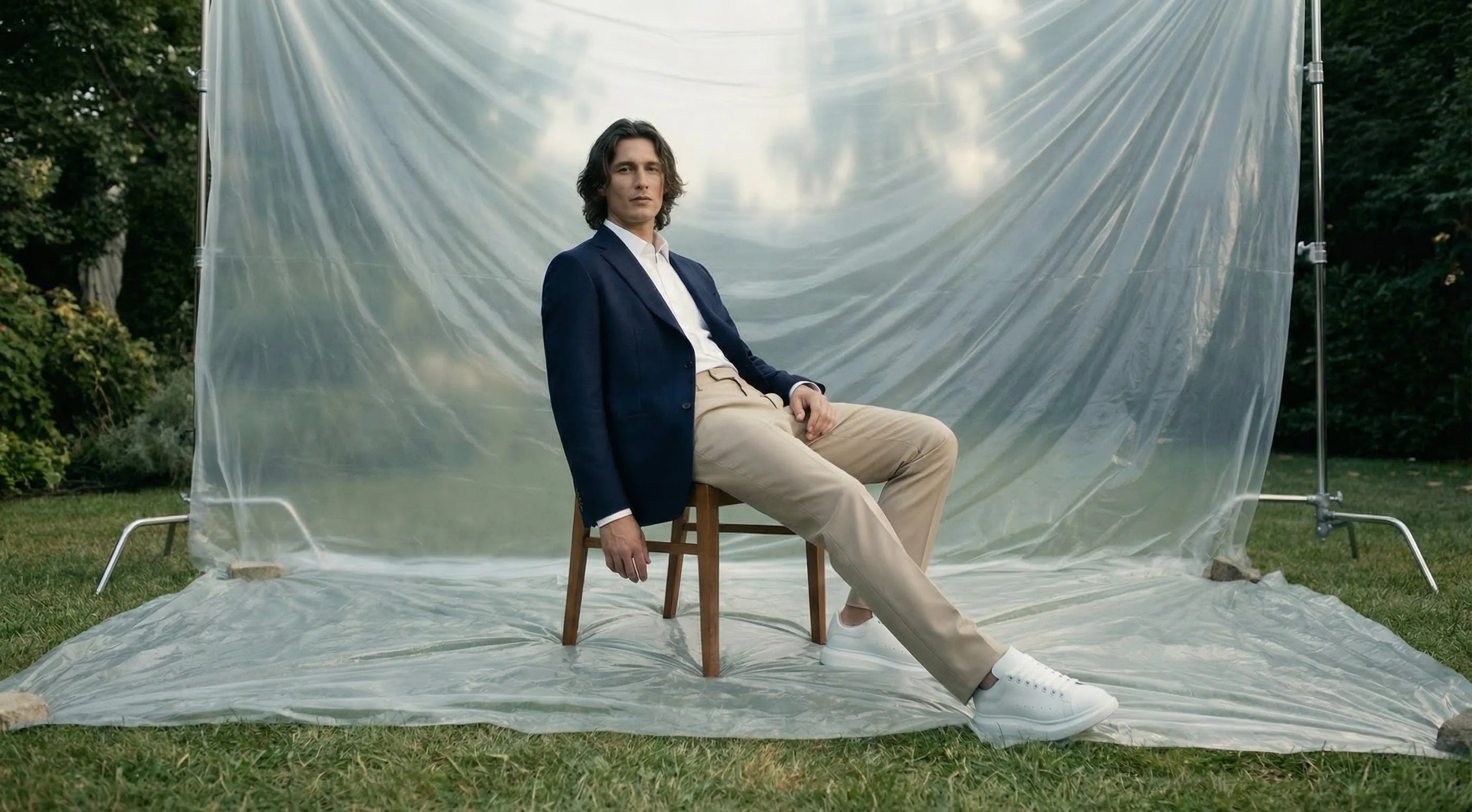 Man sitting on a chair in front of a large white sheet outdoorsslider_item_icWYVz