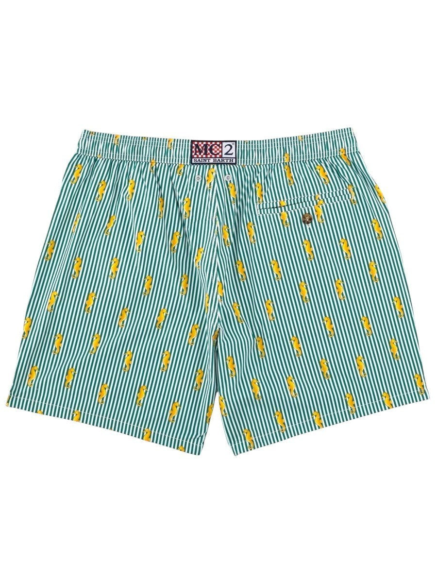 Rear view of MC2 SAINT BARTH men's swim shorts featuring green and white stripes, embroidered yellow seahorse motif and buttoned back pocket.