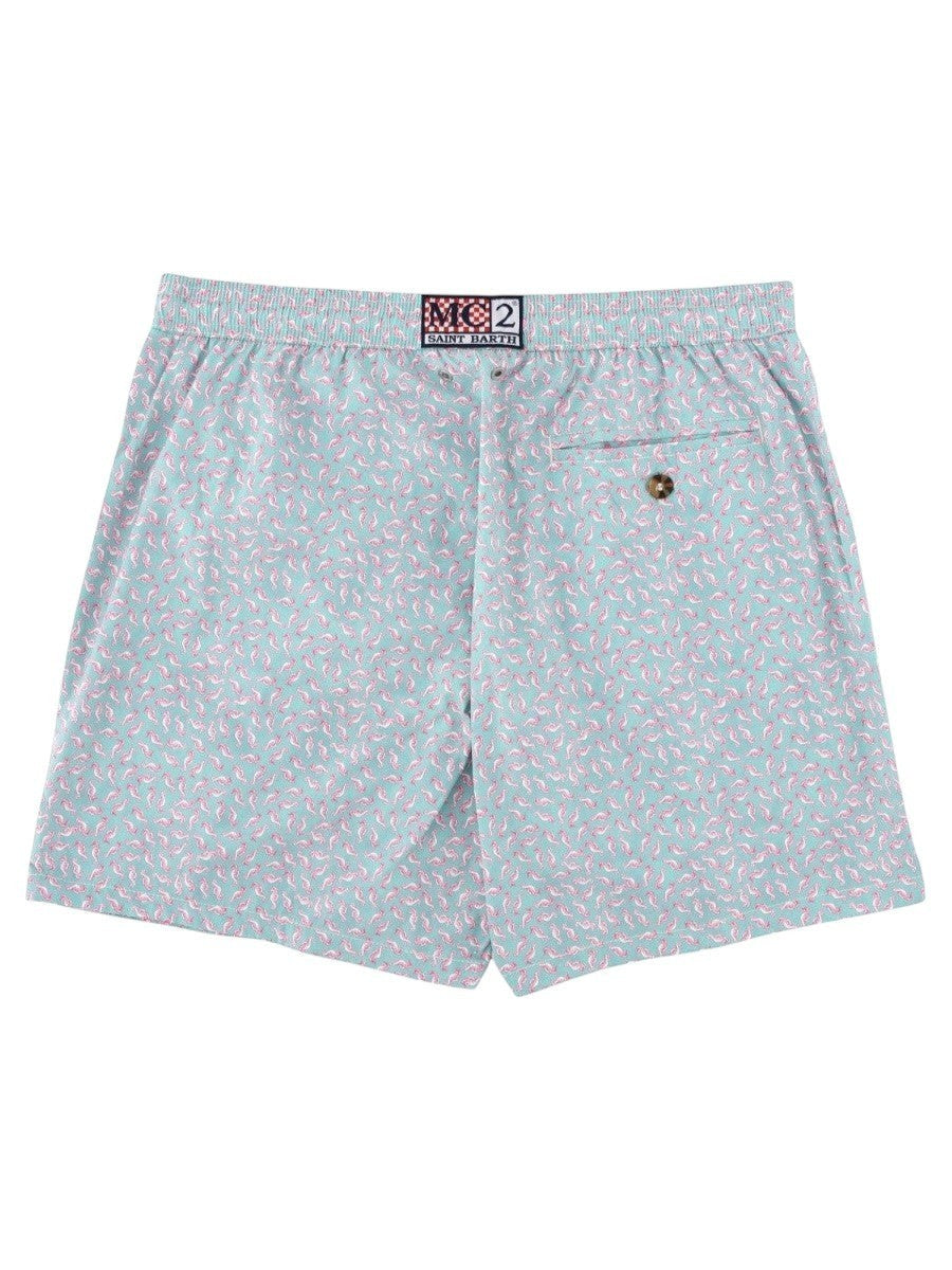 MC2 SAINT BARTH men's swim shorts featuring an all-over pink seahorse print on a light blue background with an adjustable drawstring waistband.