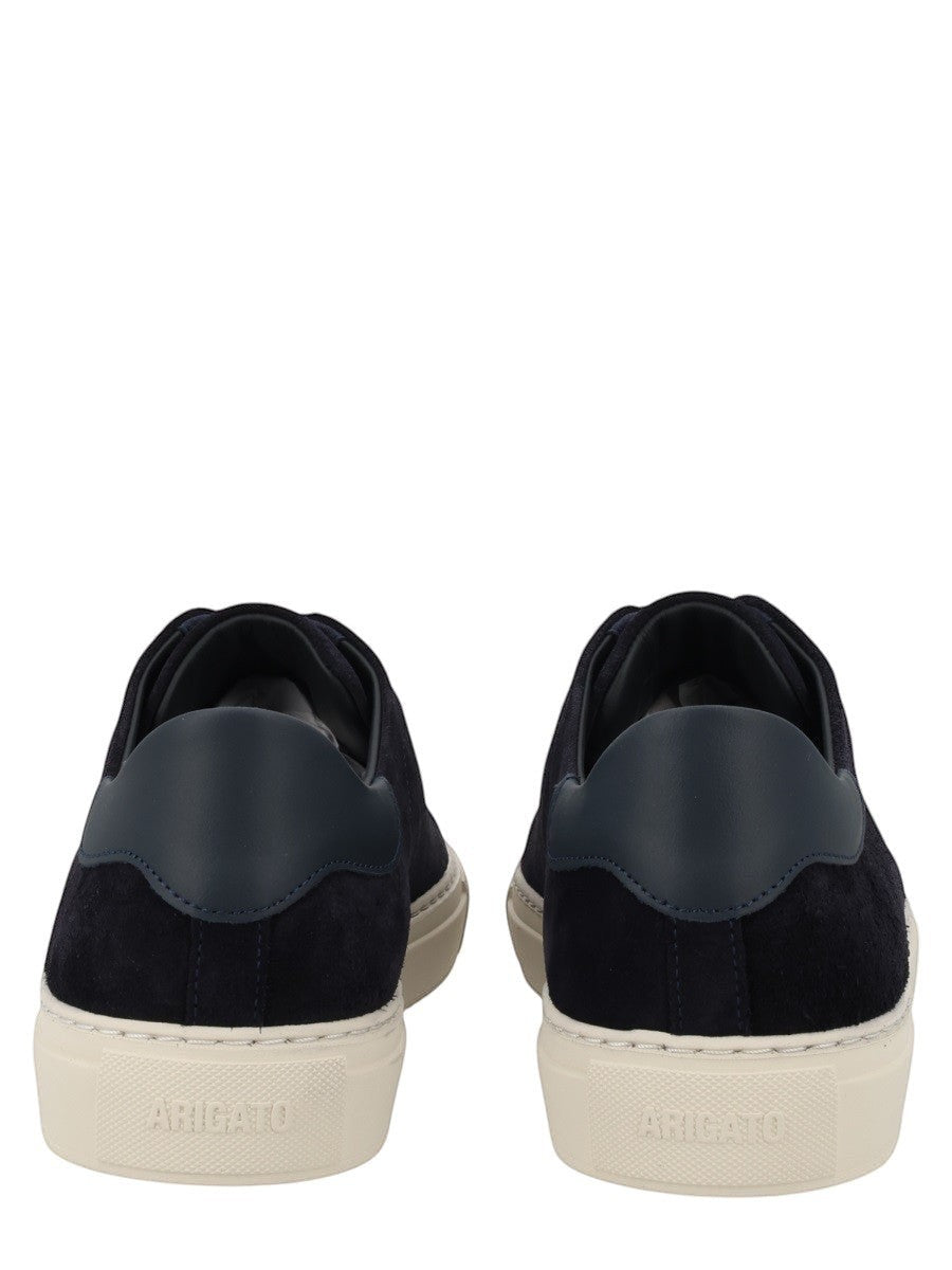 Axel Arigato navy suede low-top sneakers featuring tonal laces, gold logo detail, and an off-white rubber sole.